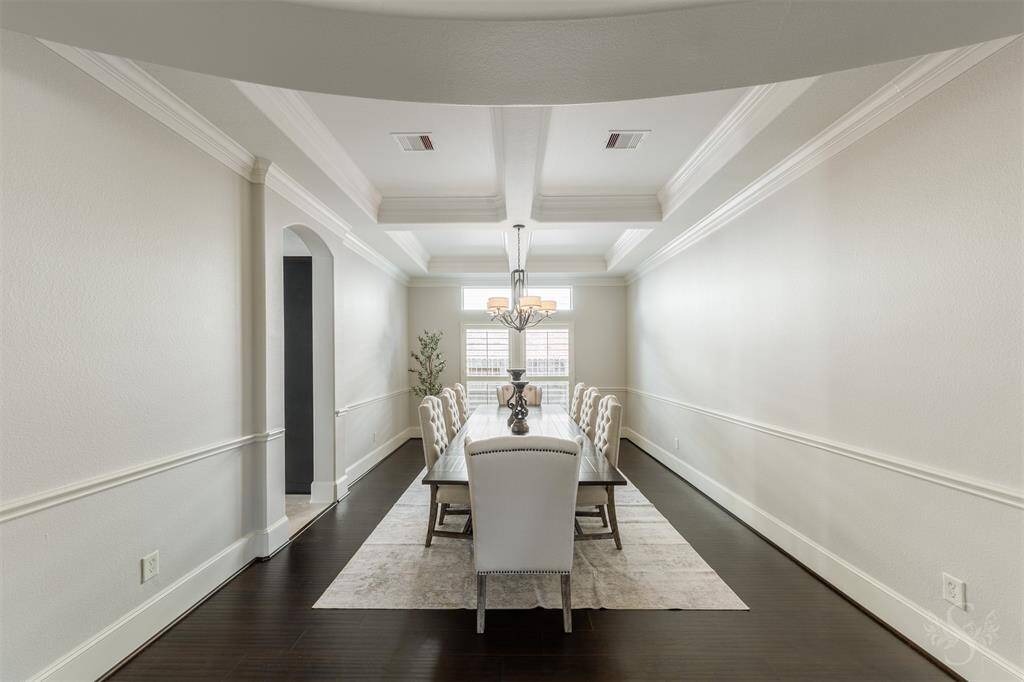 Formal dining room also with coffered ceilings, wood floors, and chair rail detailing.