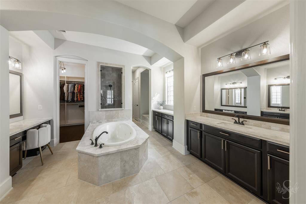Your spa-inspired ensuite featuring dual vanities, a whirlpool tub, a separate shower, dual closets, and convenient access to the laundry room through one of the closets.
