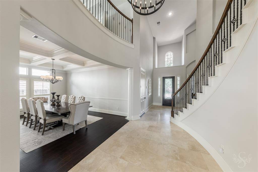 Your elegant entry with a curved staircase, high ceilings with upgraded chandelier, and travertine stone floors.