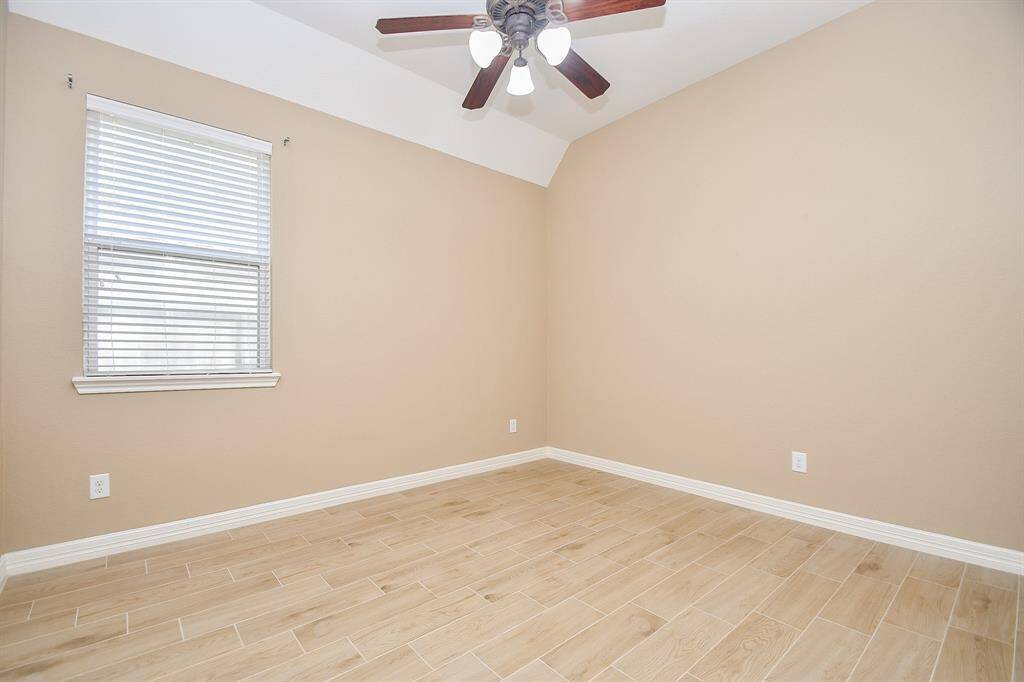 This room features neutral-toned walls, a window with blinds, light wood-look flooring, and a ceiling fan, creating a bright and airy space.