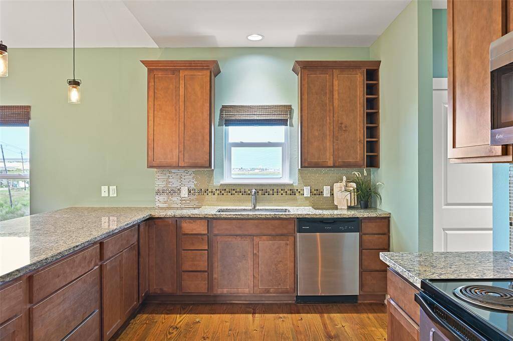 Cook up today's fresh catch in this light & bright kitchen that boasts ample storage space in the stained wood soft-close cabinetry, a deep single basin sink, a generous walk-in pantry, and stainless appliances that include a single oven, a 4 burner electric cooktop, a vent hood microwave, and a dishwasher.