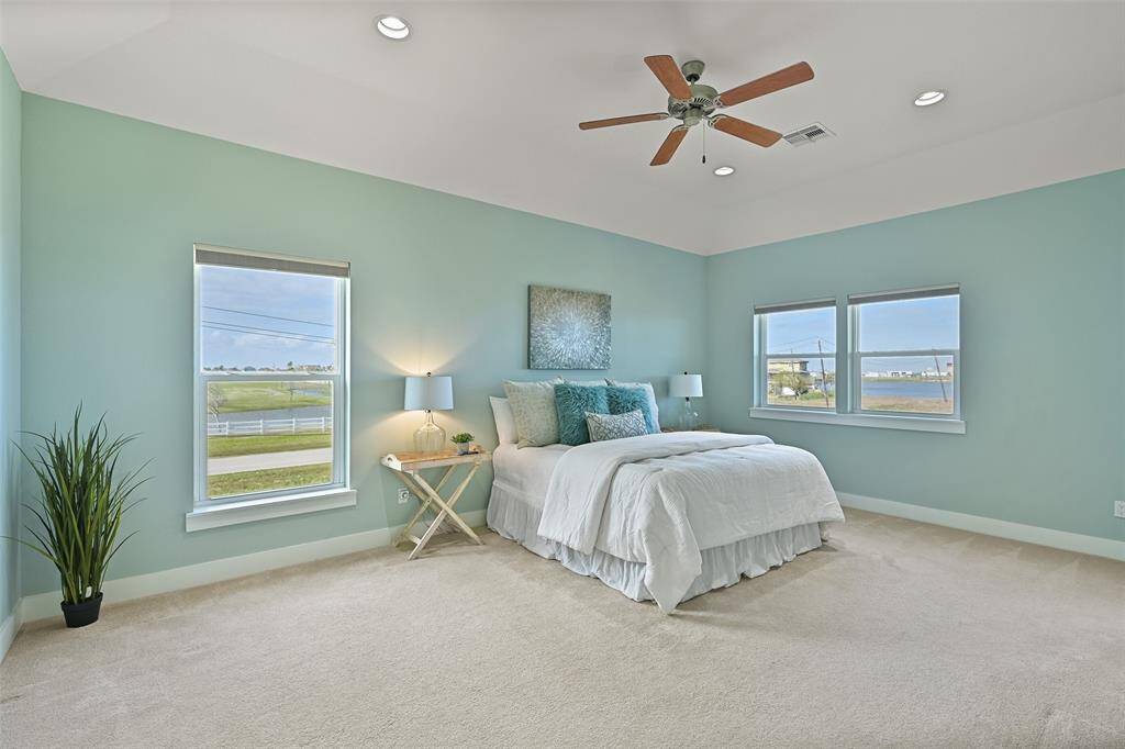 A split floorplan allows privacy for both bedrooms and this master suite is quite a retreat! It is generously proportioned and offers an elevated gambrel ceiling, a fan, recessed lights, a large walk-in closet, and windows with pleated shades and endless coastal & golf course views.