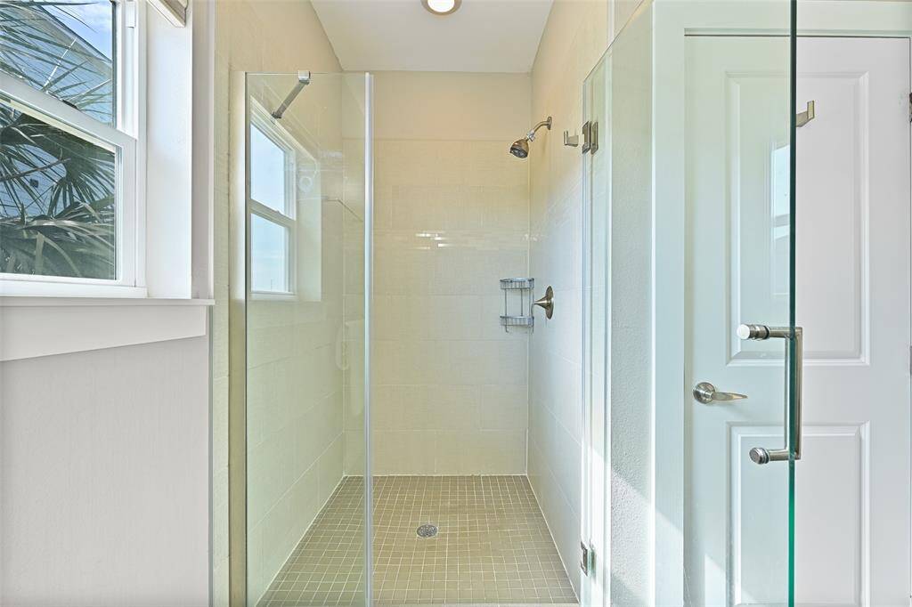 The walk-in shower in the master bathroom is oversized, featuring a seamless glass enclosure and a tile surround.