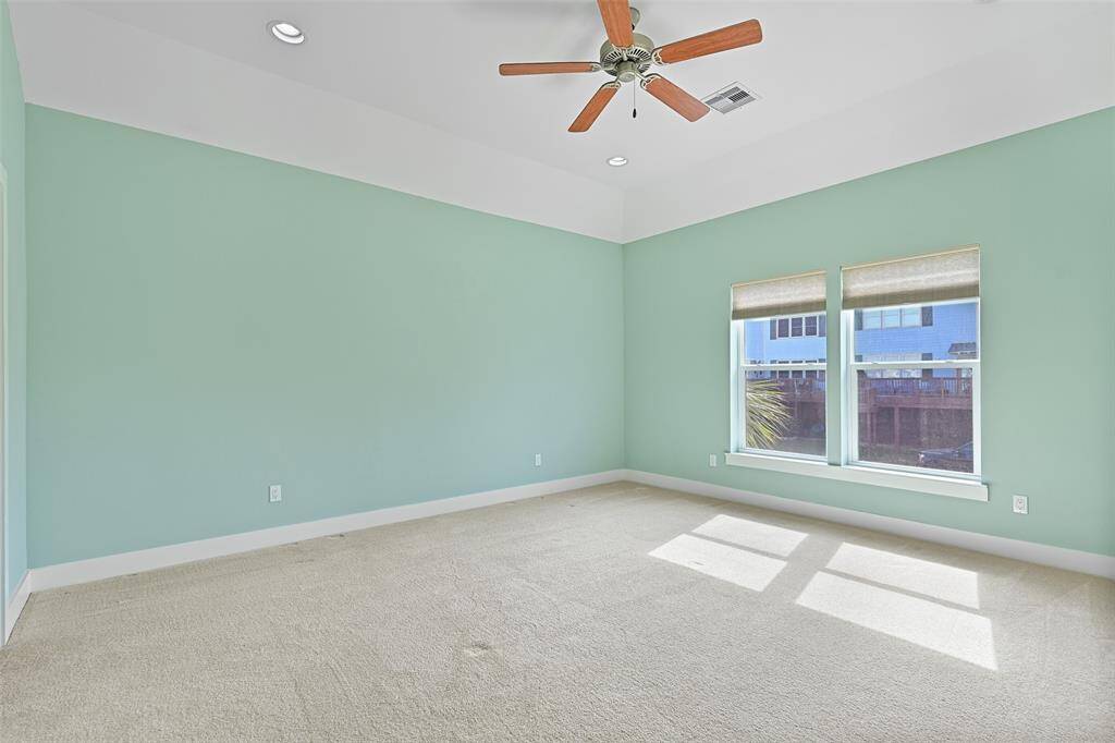 The remaining bedroom in this home is on the opposite side of the house and it is also spacious - measuring approximately 16'x15' and boasting plush carpet, a raised gambrel ceiling with a fan & recessed lights, a front-facing window, and an en-suite bathroom.