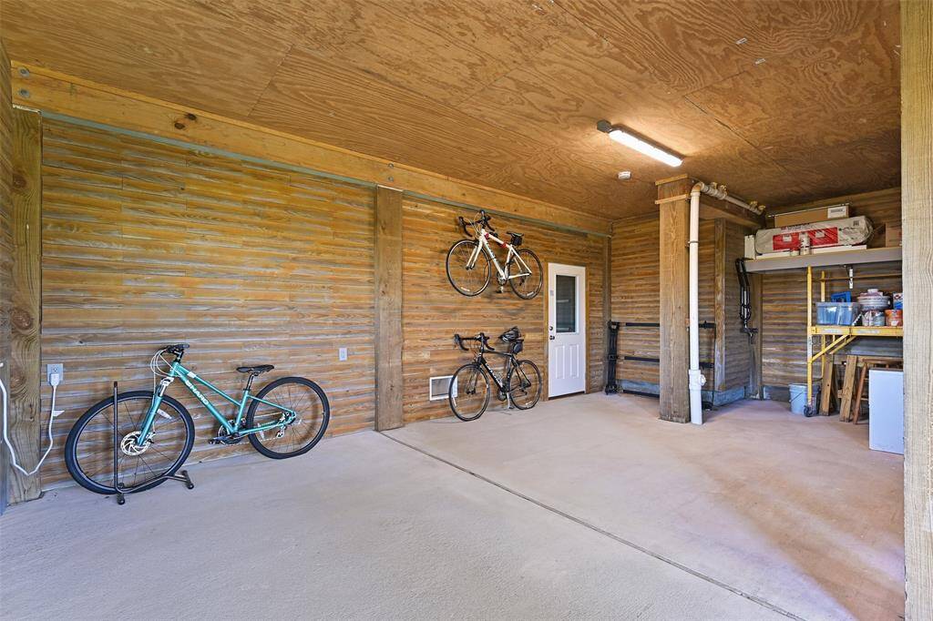 Off to the side of the 4-car tandem garage, this 27'x17' enclosed space offers a climate-controlled storage or entertainment area complete with insulated repurposed pressure-treated wood walls, impact-resistant windows & doors, flood vents, a window unit AC, and French doors to the first-floor patio.
