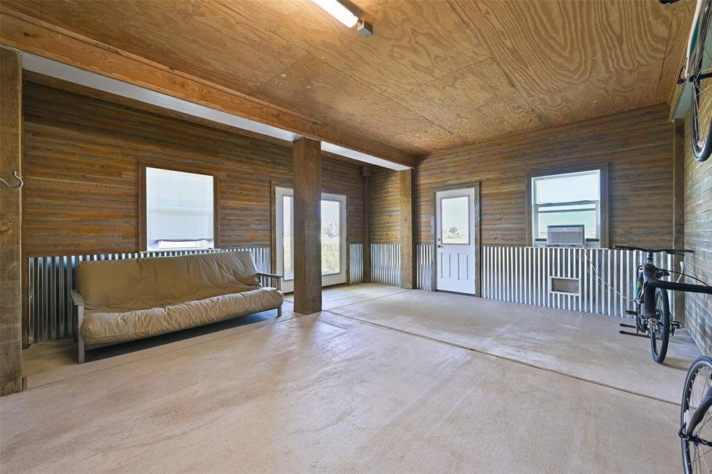 Off to the side of the 4-car tandem garage, this 27'x17' enclosed space offers a climate-controlled storage or entertainment area complete with insulated repurposed pressure-treated wood walls, impact-resistant windows & doors, flood vents, a window unit AC, and French doors to the first-floor patio.