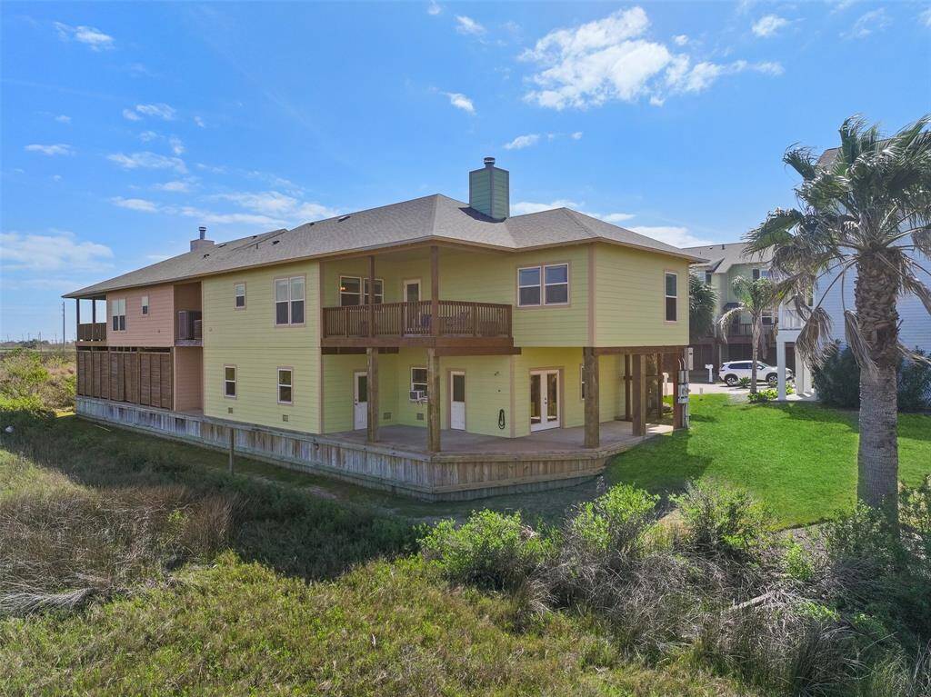 The view of the back of the home highlights some of the recent updates and improvements that include fresh exterior paint and stain, a new roof with an ice & water shield, a whole home generator with a gas line, an outdoor shower, and ample outdoor living space.