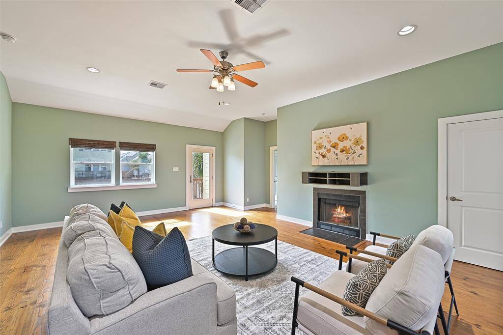 From the exterior staircase at the front of the home, step through the full-panel glass door into the main living space where you'll find a lighted ceiling fan, recessed lights, solid pine floors, and a streamlined wood-burning fireplace with a tile surround.