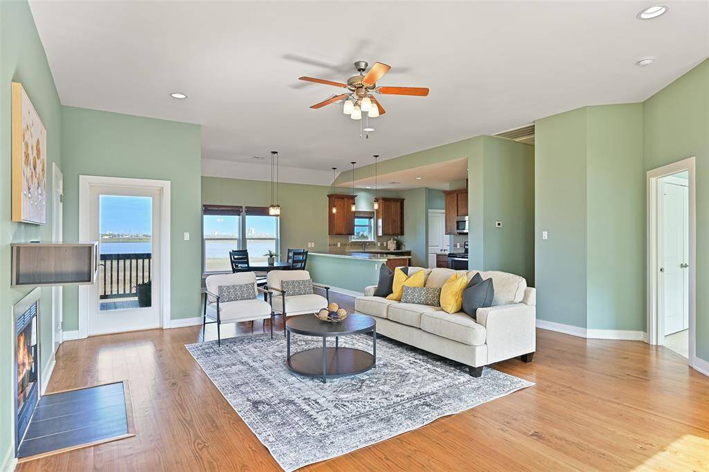 An alternate view of the living space highlights the seamless transitions between the family room, dining area, & kitchen, as well as the numerous energy-efficient, impact-resistant windows and doors that flood the space with natural light and showcase peaceful panoramic views of the bayou & golf course.
