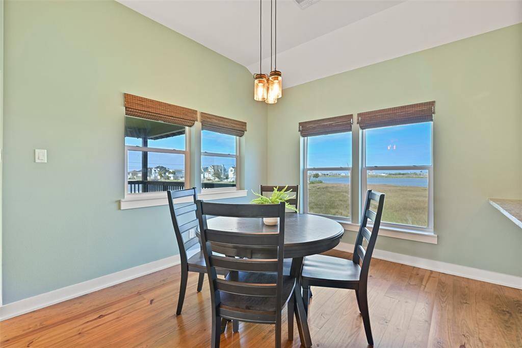 Tucked between the family room and kitchen, this dining area offers pine wood floors, a trio of modern pendant lights suspended from the 10-foot ceiling, and windows overlooking Sydnor Bayou & the golf course. If you'd rather dine al fresco, just step outside to the breezy balcony!