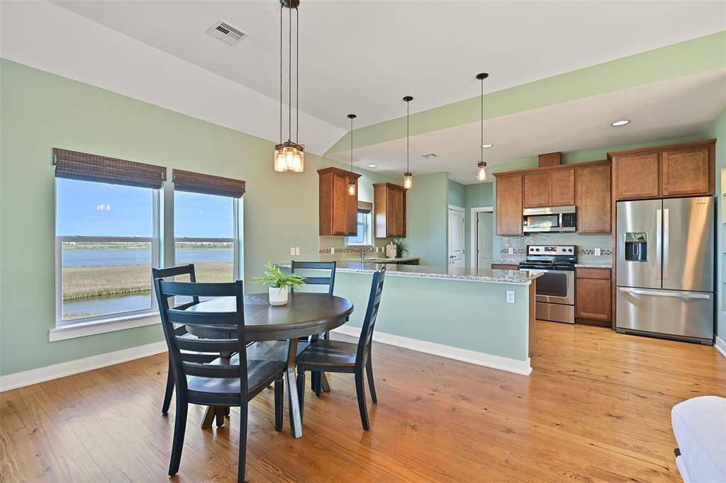 Tucked between the family room and kitchen, this dining area offers pine wood floors, a trio of modern pendant lights suspended from the 10-foot ceiling, and windows overlooking Sydnor Bayou & the golf course. If you'd rather dine al fresco, just step outside to the breezy balcony!