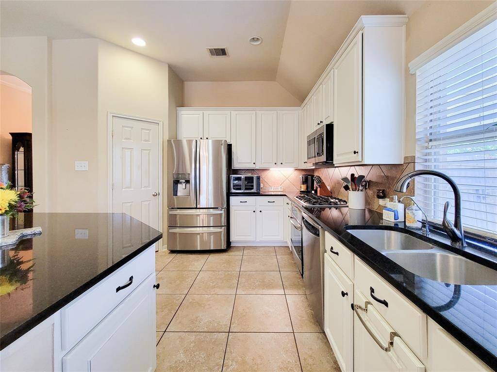 Gorgeous white kitchen cabinetry with black hardware to match the granite countertops