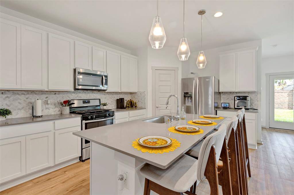 The kitchen boasts sleek stainless steel appliances and an abundance of cabinets for ample storage, with a convenient pantry tucked behind a closed door for added functionality.