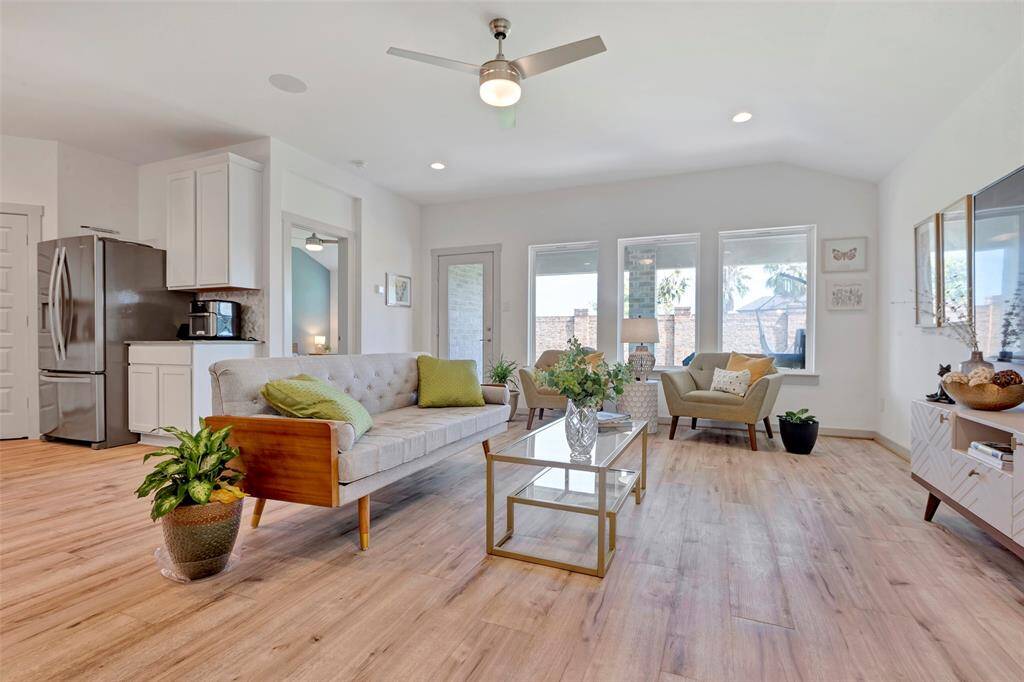 The living area features expansive glass windows that flood the space with natural light, complemented by a ceiling fan for added comfort, while offering a delightful glimpse of the back patio.