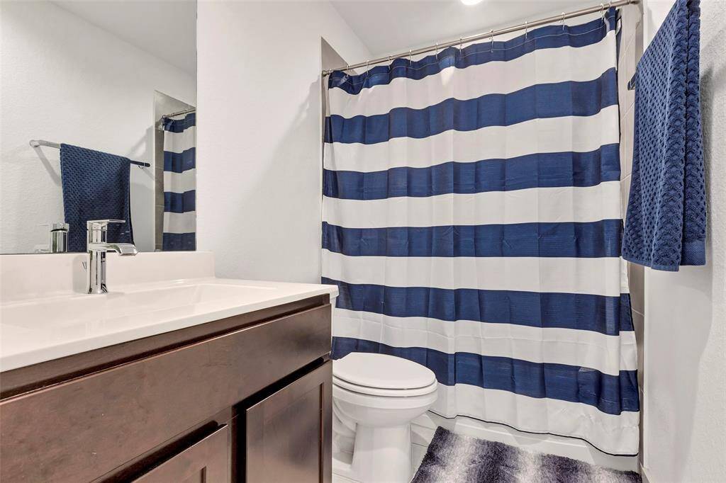 This secondary bath features a convenient tub and shower combo, a sleek single sink vanity, and a toilet, offering both functionality and comfort.