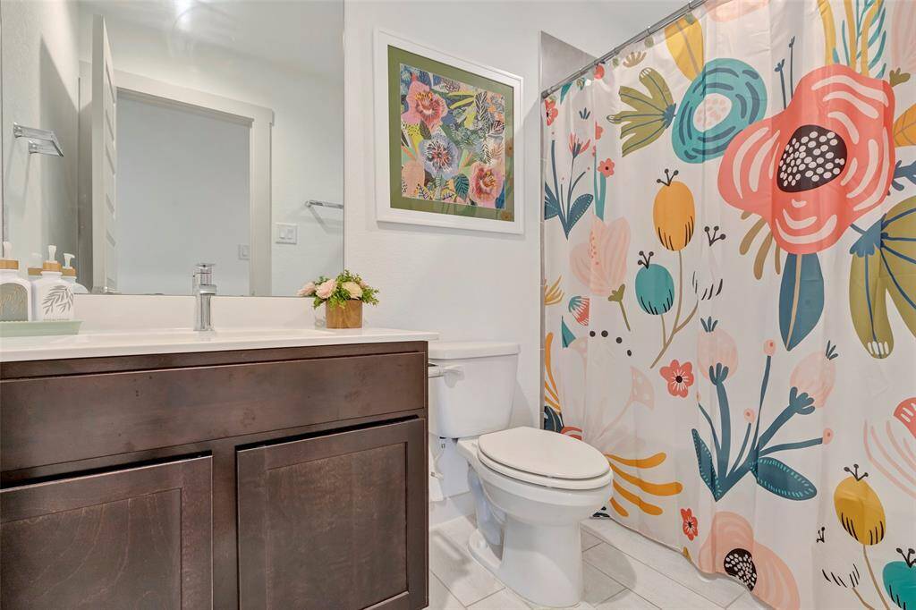 This additional secondary bathroom features a tub and shower combo, a single sink vanity with a cabinet for storage, and a toilet, combining practicality with comfort.