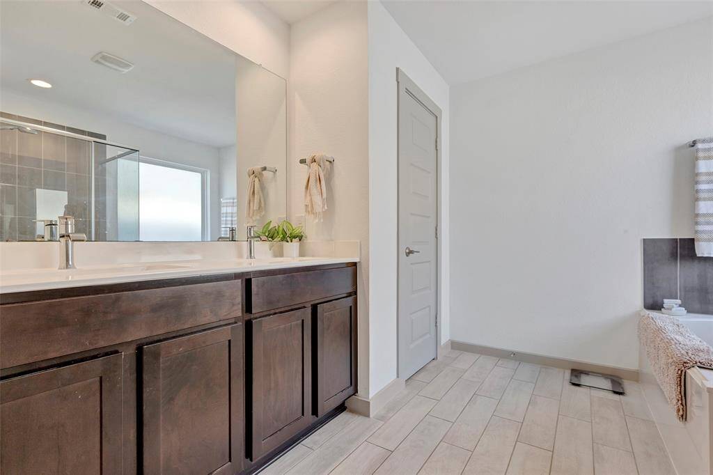 The primary bathroom features a large glass mirror above the double sinks, complemented by spacious cabinets for ample storage.