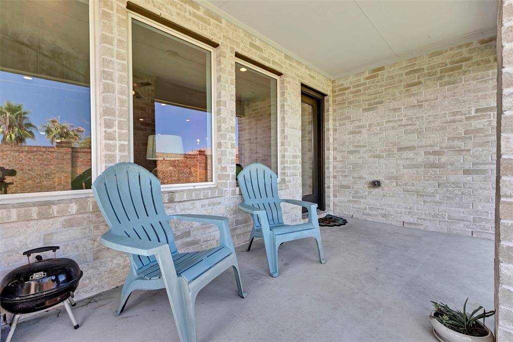 This back patio exudes a laid-back ambiance, ideal for spacing out or enjoying a chat while overlooking the lush green backyard.