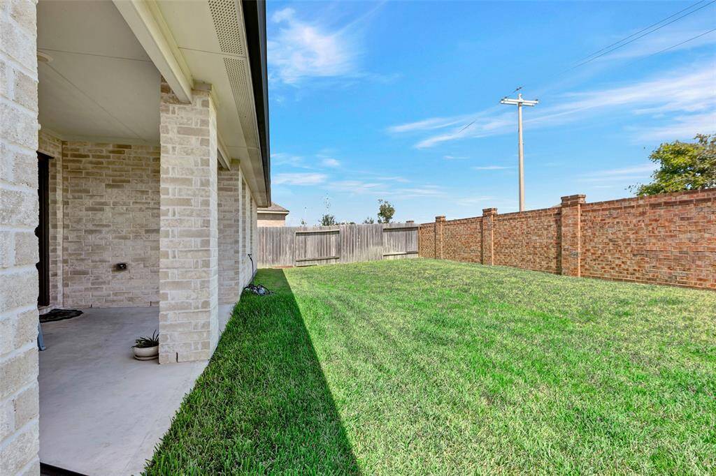 The backyard is securely enclosed by a tall brick and wooden fence, providing privacy and a peaceful oasis for relaxation and play.