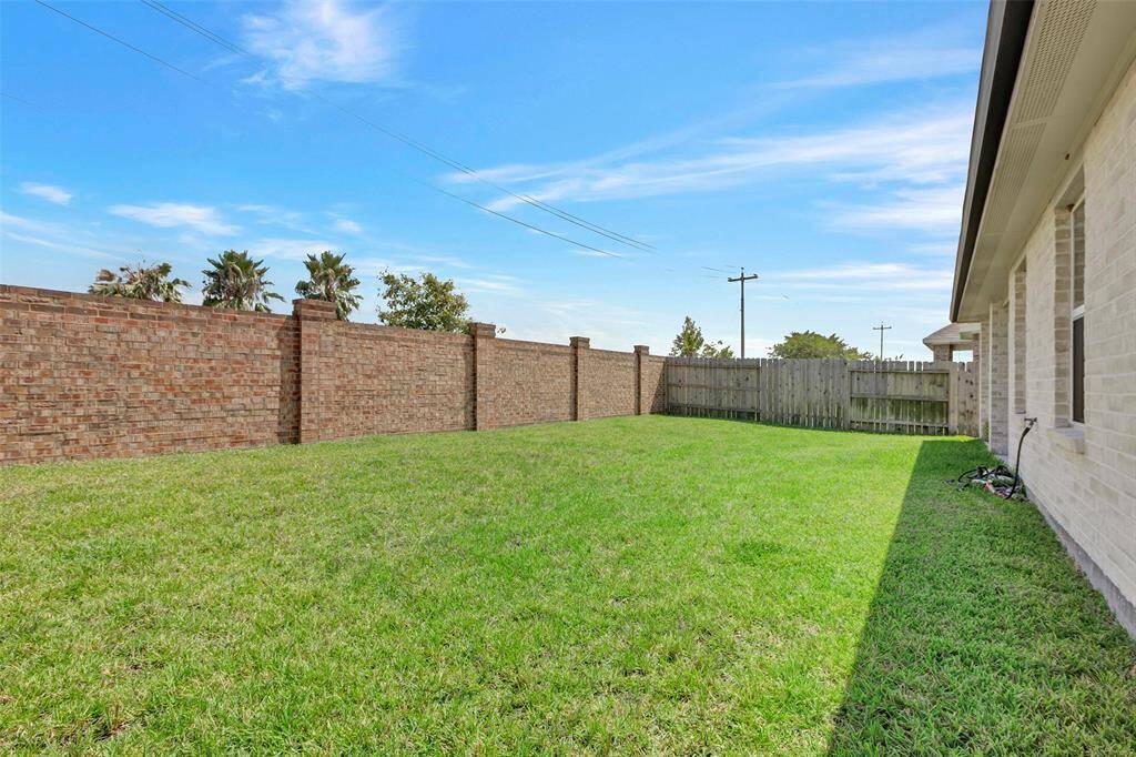 Highlighting the elegant brick wall and wooden fence that beautifully enclose the backyard.