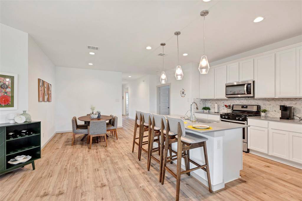 The kitchen and dining area feature a central island that serves as both a functional sink and a charming breakfast bar, perfect for casual meals and gatherings.