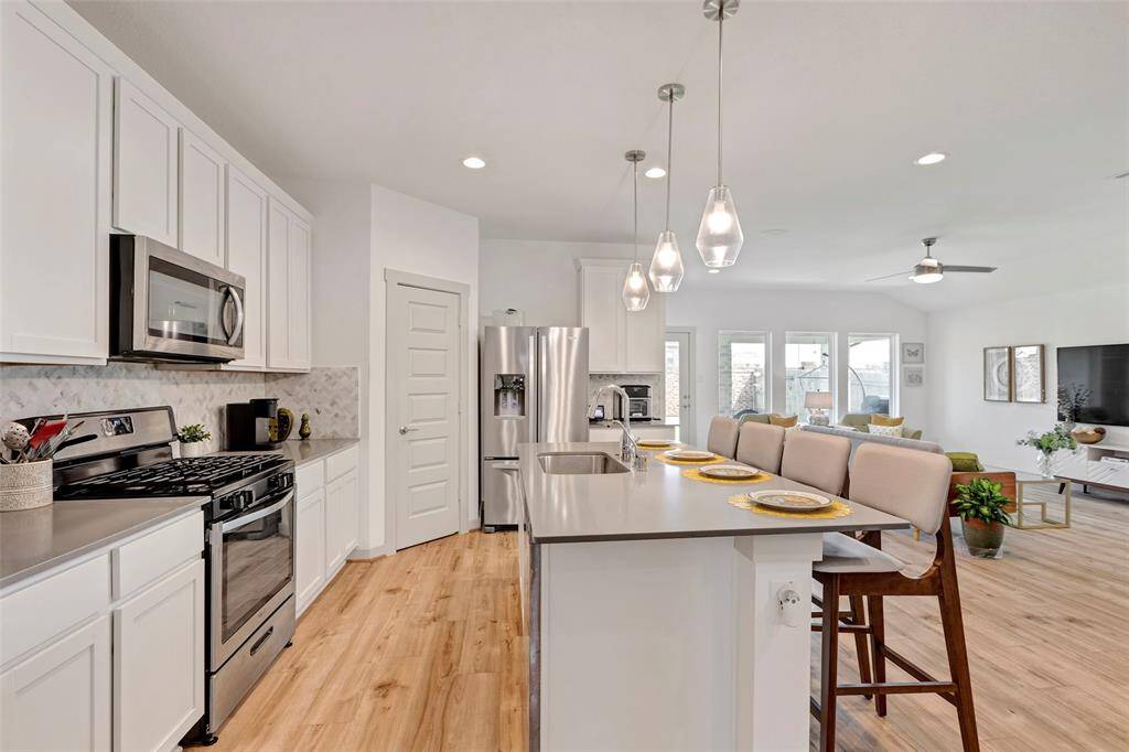 This kitchen offers a delightful view, showcasing a glimpse of the back patio and the spacious living area in the background.