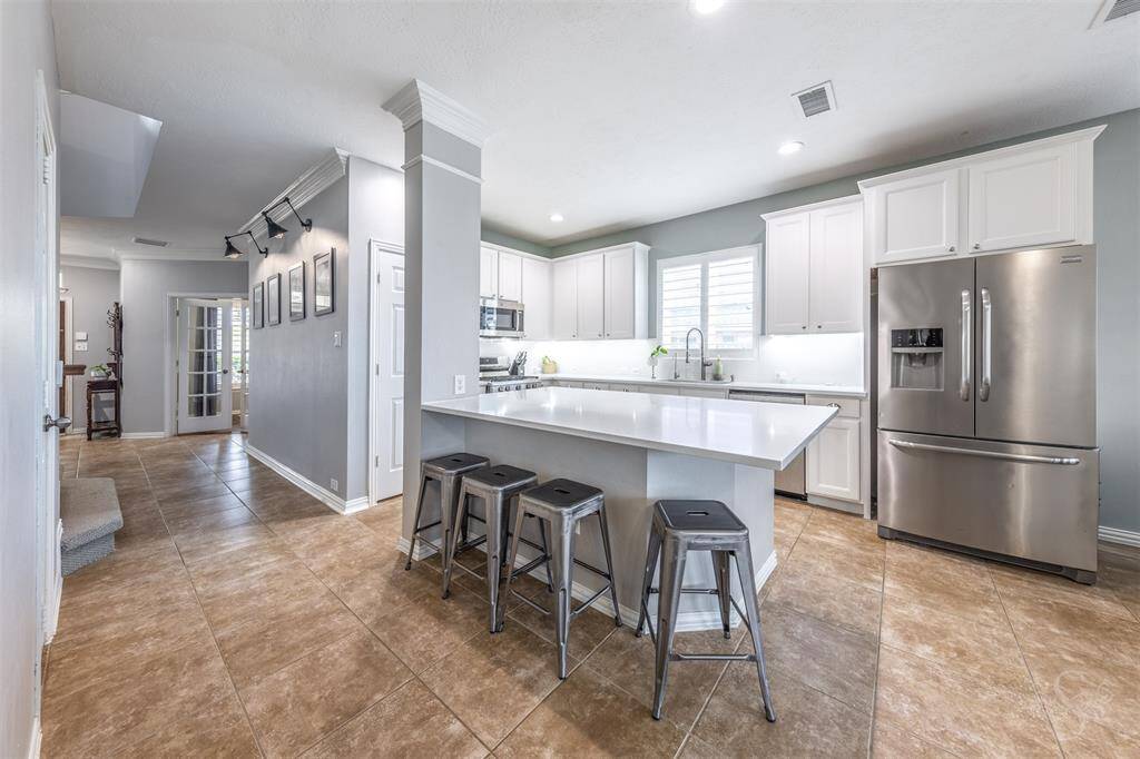Your kitchen with a large island, new quartz counters, new tile backsplash, under cabinet lights, stylish white cabinet paint, filtered water at the sink, new light fixtures, and a huge walk-in pantry with built-in spice racks and organization.