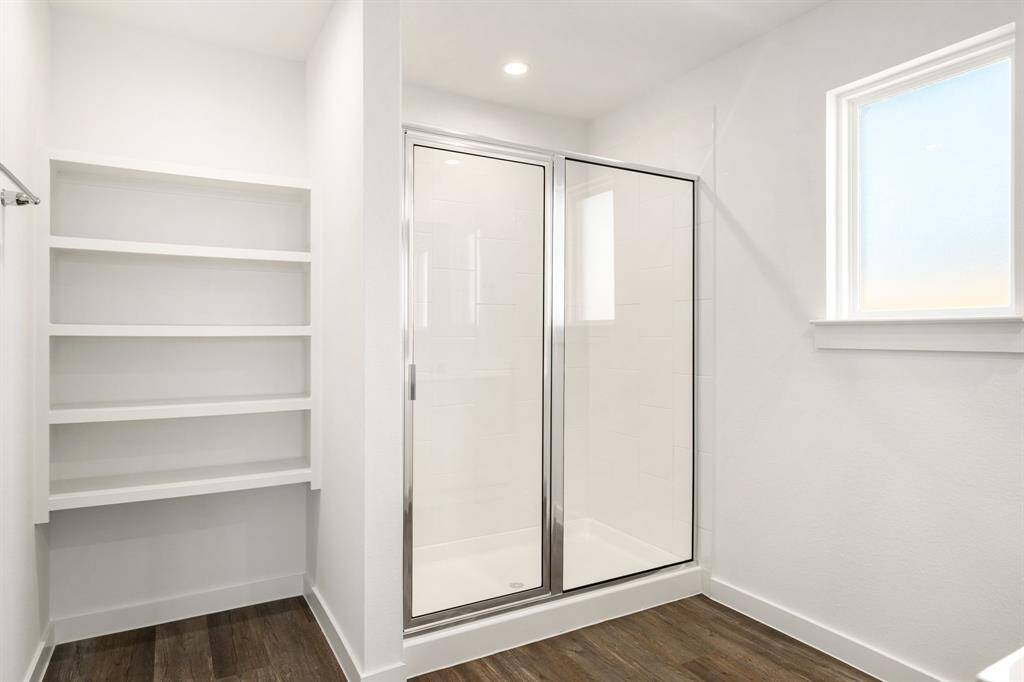This additional view of the primary bath showcases the oversized walk-in shower with tile surround, perfect for soaking after a long day, and a convenient linen nook.