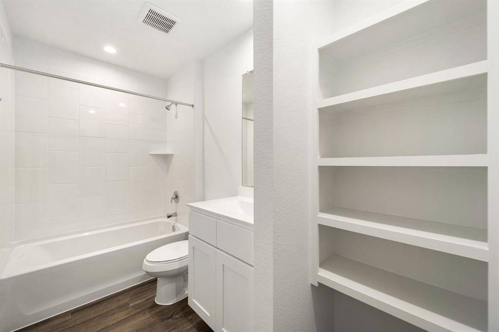 Secondary bathroom features light countertops and cabinets, shower/tub combo with tile surround, large mirror, sleek fixtures and modern finishes, plenty of space to accommodate any visiting family or guests.
