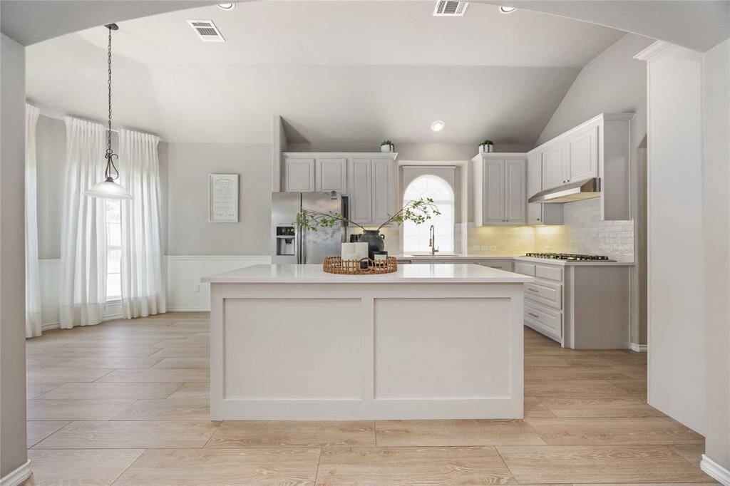 Bright and stylish view of the fully remodeled kitchen, featuring sleek quartz countertops, oversized island, freshly painted cabinets, and updated hardware for a modern yet inviting feel.