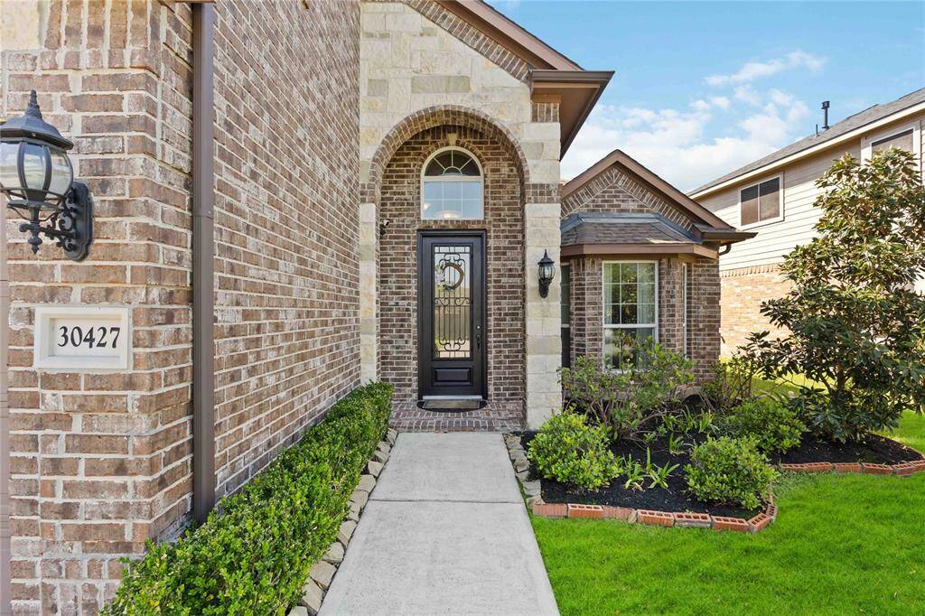 An inviting brick and stone entrance surrounded by beautiful landscaping, welcoming you home with charm and warmth from the moment you arrive.