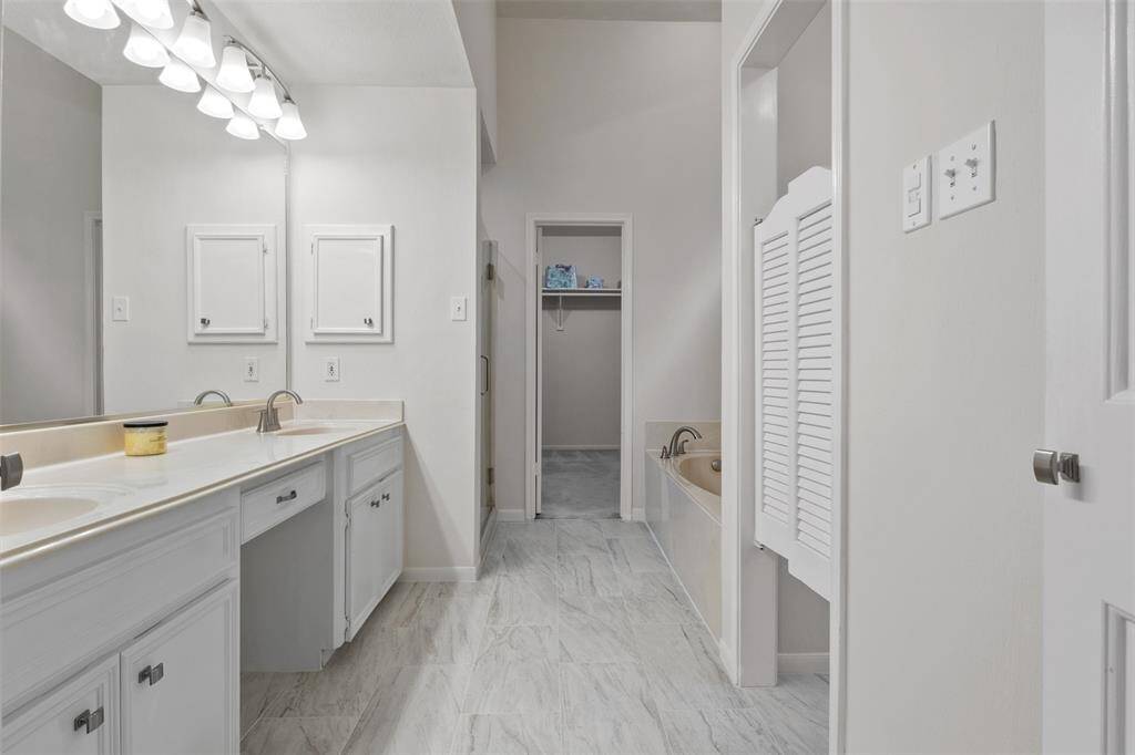 Primary bathroom is a true retreat, featuring newly finished tile throughout and a large, spa-like atmosphere. Enjoy the sleek new glass shower door, a spacious soaking tub, and a walk-in closet. It's the perfect
