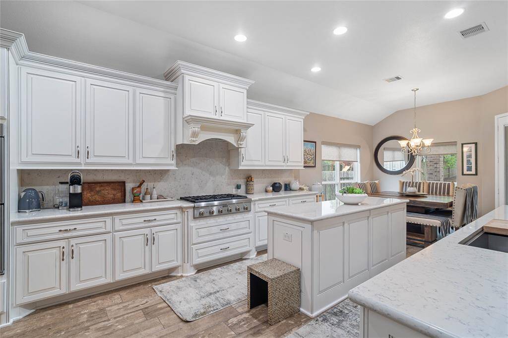 Island kitchen with custom cabinets, hard surface countertops, and tiled backsplash.
