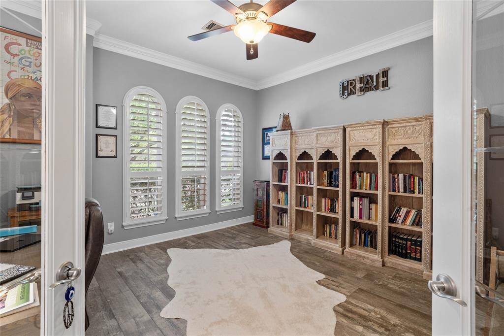 Spacious home office with double door entry, plantationshutters, and crown molding.