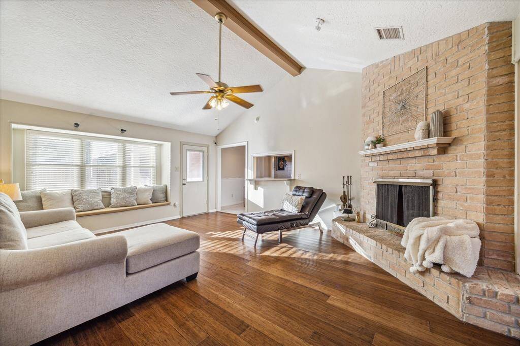 What a beautiful space to gather with family and friends. This open family room features hardwood flooring, neutral paint, a soaring ceiling with a wood beam and lit fan, and a romantic gas-log fireplace.