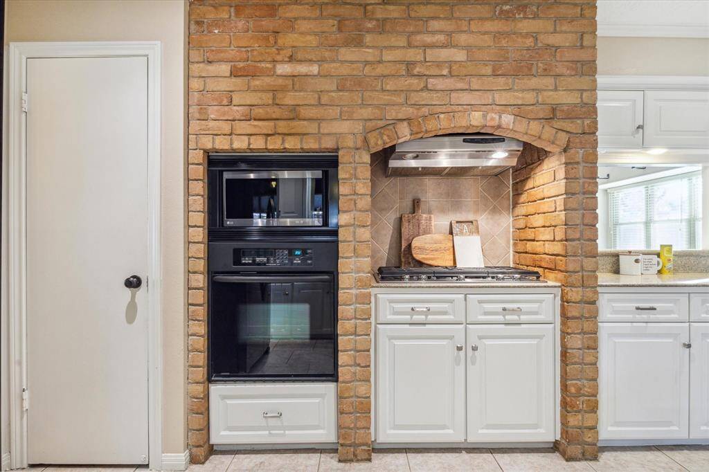 The kitchen features a stunning brick surround that frames the built-in oven, microwave, and gas cooktop. What a stylish and unique feature!