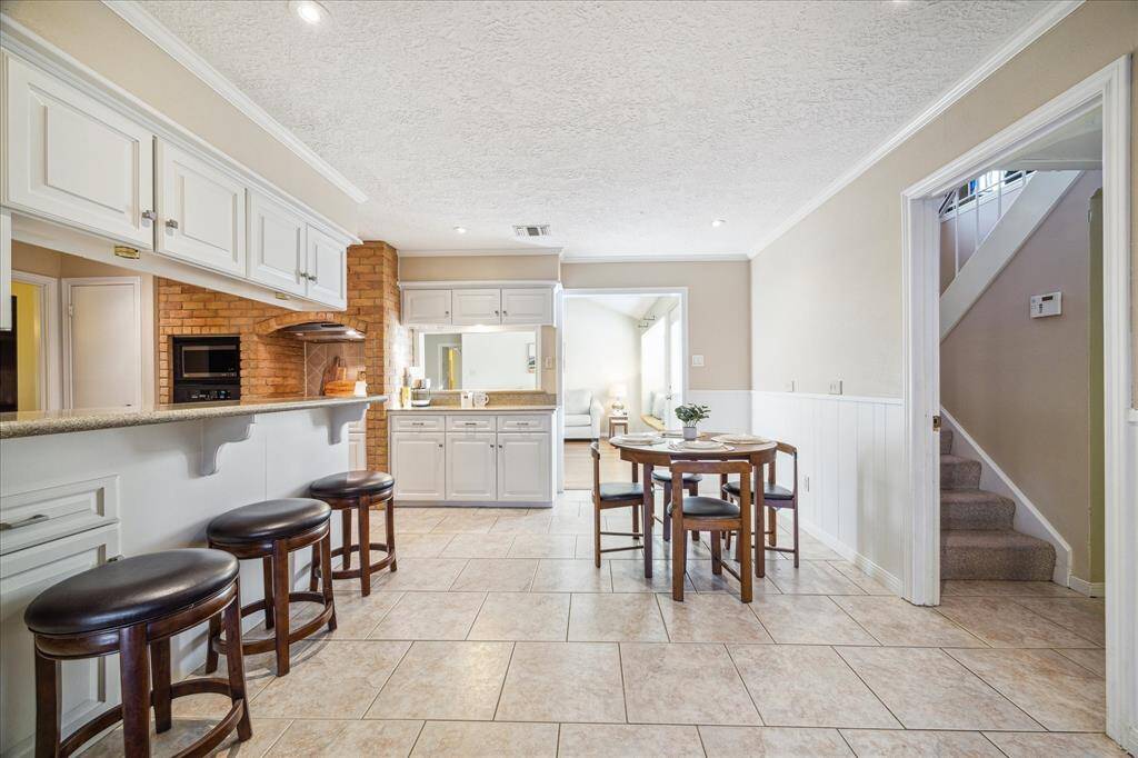 An alternate view of the breakfast shows the utility room and half bathroom to the right and stairs leading to guest quarters with a living room, bedroom, and a full bath.