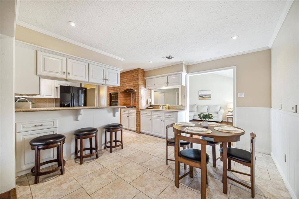 Savor morning coffee in this spacious breakfast area with tile flooring, wainscoting, and neutral paint.