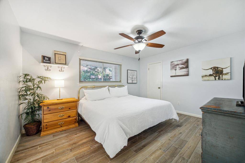 This spacious guest bedroom offers beautiful wood-look tile flooring, neutral paint, an updated ceiling fan, large closet and easy access to a full bathroom.
