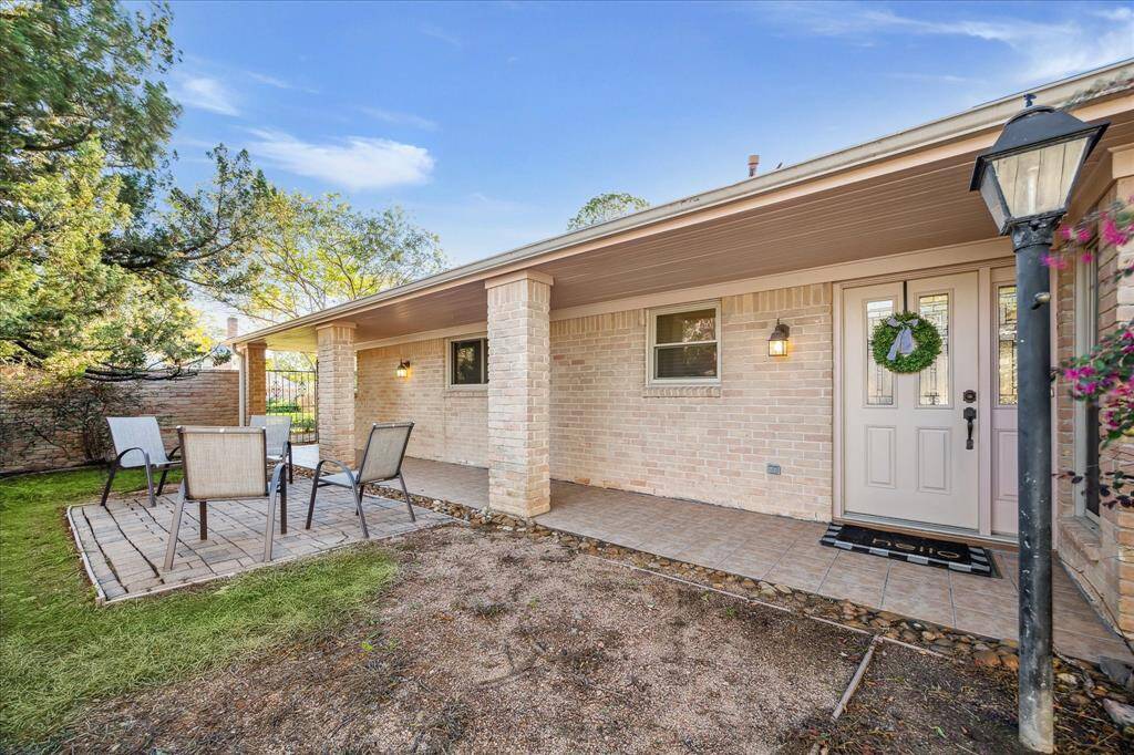 An expansive covered patio runs along the side of the home behind the front entry gate. It offers tile flooring, handsome coach lighting and provides a great setting to enjoy morning coffee or a nightcap with your favorite person.