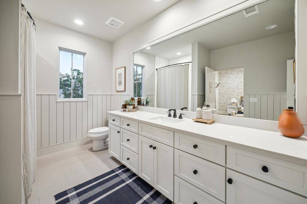 Bathroom 4. Large vanity area and features wood paneling on the walls.