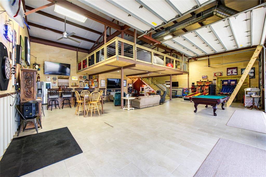 WHAT A TREAT! This 2-story air conditioned space offers a tankless hot water heater, tile flooring, insulated walls, roll top doors, updated electrical/lighting, fans, a full bar, a loft, a kiddy club space under the stairs and a full bath! Ladder on right leads to additional storage space over carport area.