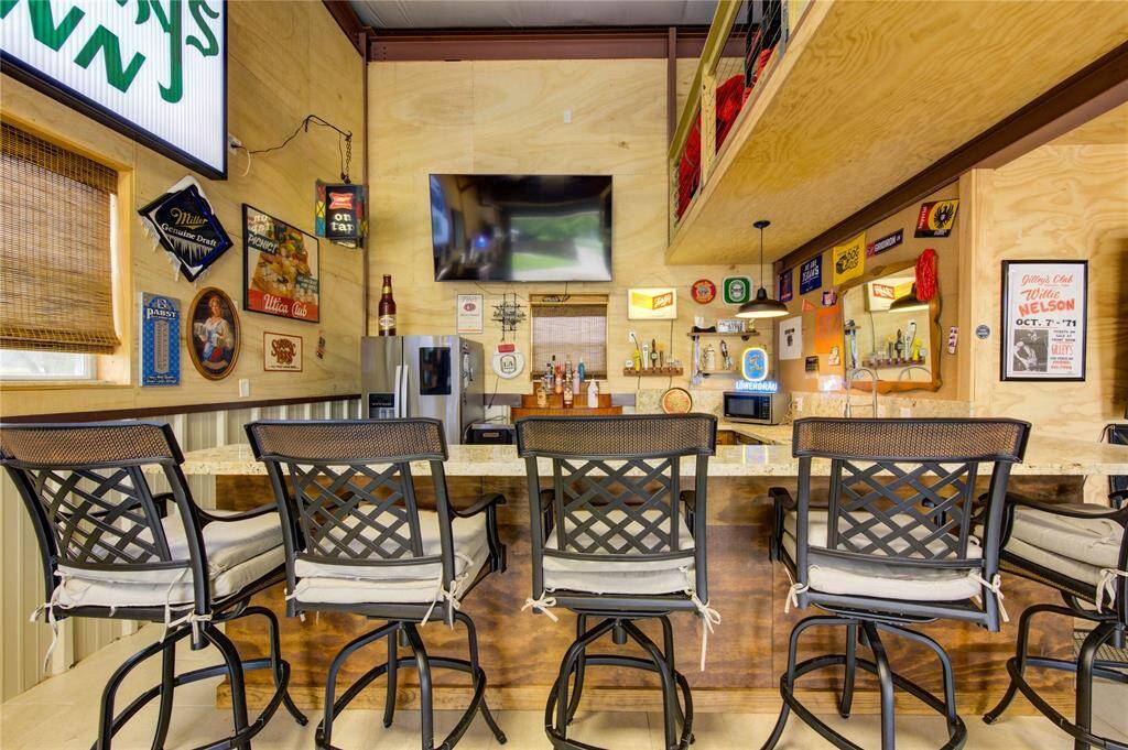 Complete with farm sink and separate chilling sink for icing Champaign, a dishwasher, abundant cabinets, and even reinforced granite on the counter tops (because there are moments when you may want to dance on the bar), this area is a true centerpiece of so many gatherings!! All decorations, wall hangings, commercial refrigerator, tv's and personal items are excluded from the sale.