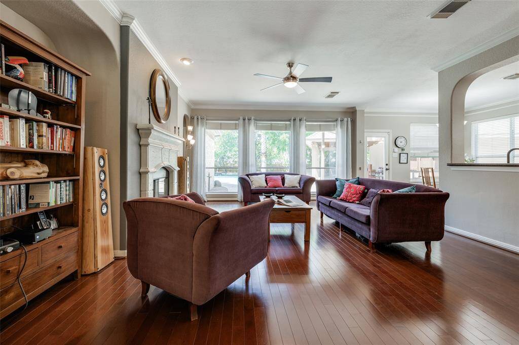 Living room with wall of windows out to a beautiful back yard, hardwood floors, open through to kitchen