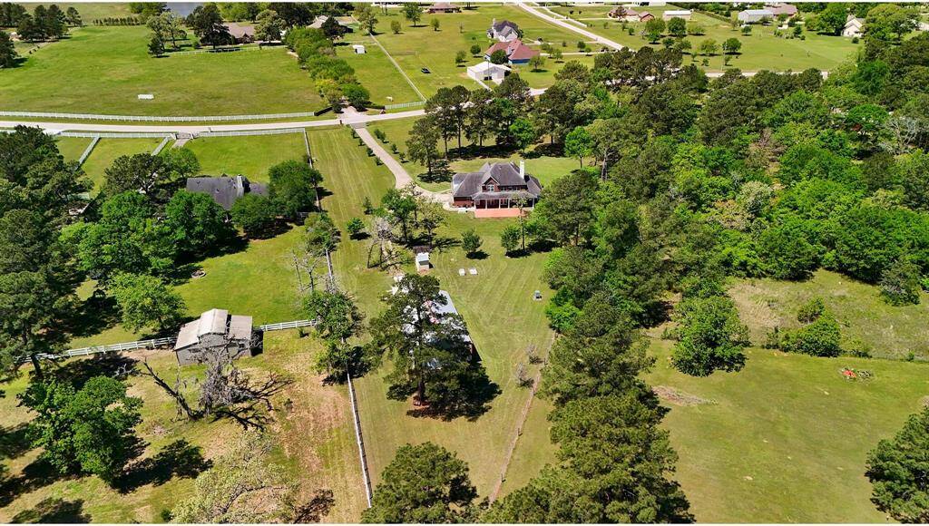 This view offers a stunning perspective of the expansive 3+ acre property. In the foreground, you'll find a spacious barn and a detached office—perfect for work or hobbies—while the all-brick home sits elegantly toward the front of the lot, complete with a covered back patio for relaxing or entertaining.