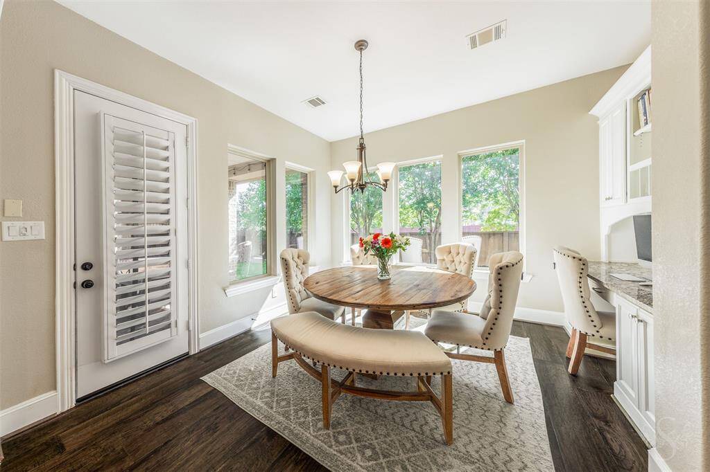 This is a bright breakfast area with large windows offering natural light and garden views. The space also includes a built-in desk with built-in cabinetry.