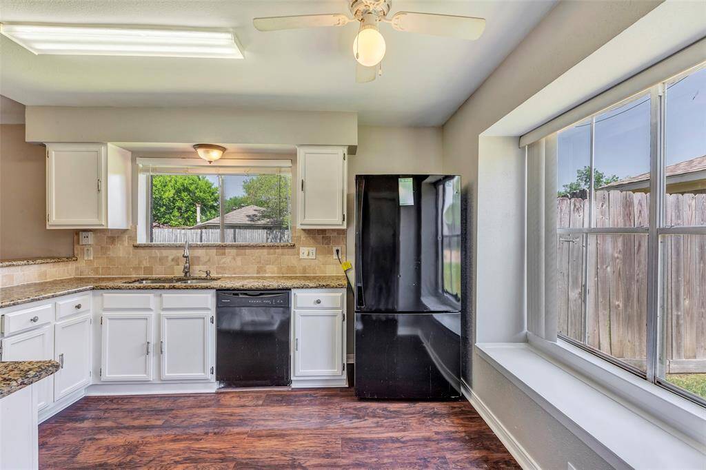 A wider view of the kitchen, bathed in natural light streaming through expansive glass windows, creating a warm and welcoming atmosphere.