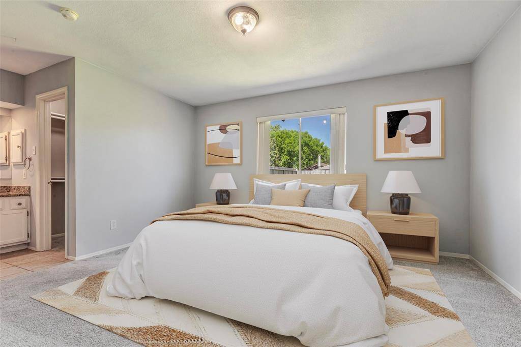 The primary bedroom features plush carpeted floors, with the bathroom and walk-in closet conveniently located to the left, enhancing both comfort and functionality. (Virtually Staged)