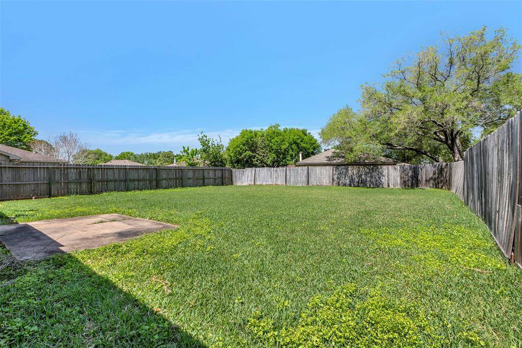 Step into the expansive backyard, a private retreat adorned with lush green grass and enclosed by a tall wooden fence, offering a serene and tranquil outdoor space.