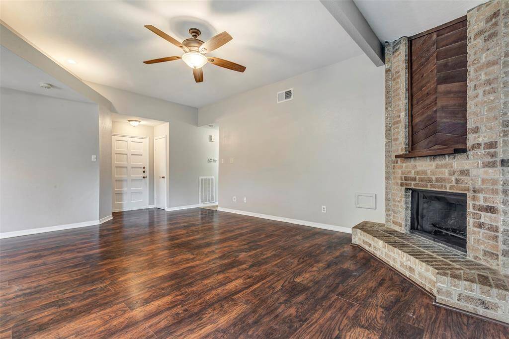 The living room features warm laminated wood flooring and a charming gas-and-wood burning fireplace—perfect for cozying up on chilly days.